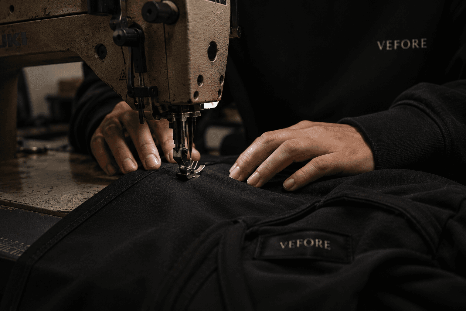 Black garment being sewn at an industrial sewing machine